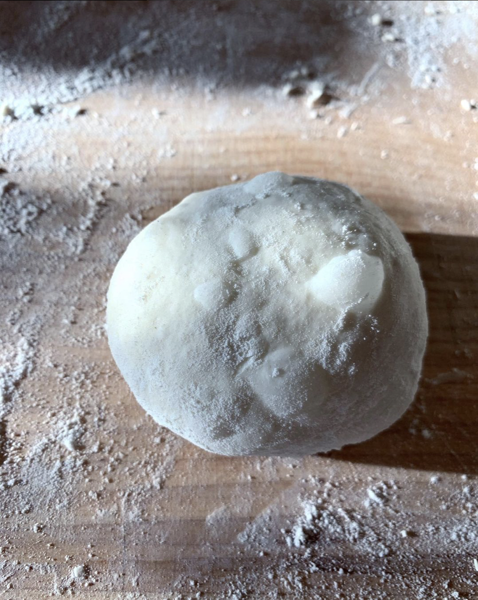 round of dough being shaped with a big bubble, taken in early morning sunlight